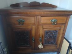 A sideboard having twin drawers over enclosed cupboards with carved decoration measuring
