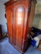 A double wardrobe with carved decoration, the door opening to reveal a hanging rail and two drawers,