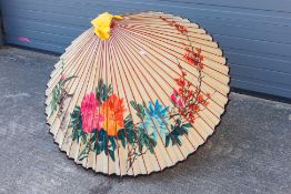 A large hand painted parasol decorated with birds and flowers.