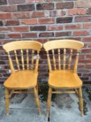 A pair of matching solid pine dining chairs.