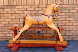 A vintage solid wood rocking horse on trestle base with leather tack, approximately 105 cm x 140 cm.