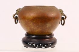 A Chinese bronze censer of bulbous form, twin mask handles with suspended rings,