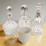 Three crystal decanters and a Lladro collector's society porcelain cup, dated 1997.