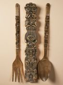 An oversized wooden fork and spoon, length 92 cm, together with a carved totem.
