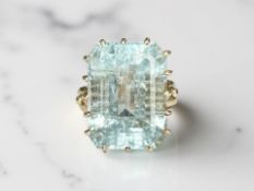 A blue topaz ring, the large emerald-cut stone in a claw setting,