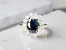 An 18ct gold sapphire and diamond cluster ring, the oval-cut sapphire weighing an estimated 2.