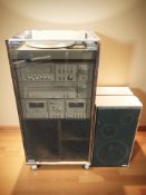 An Amstrad hi-fi system in cabinet and a pair of teak effect speakers.