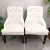 A pair of contemporary chairs in deep buttoned light grey upholstery.
