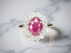An 18ct gold ruby and diamond cluster ring, the faceted oval ruby weighing an estimated 2.