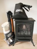 A small electric fire and a Shark vacuum cleaner.