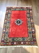 An Eastern geometric woolen rug on red ground, 191 cm x 132 cm.