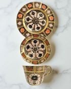 A Royal Crown Derby Imari porcelain teacup, saucer, and plate trio, filled gold band border,