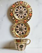 A Royal Crown Derby Imari porcelain teacup, saucer, and plate trio, filled gold band border,
