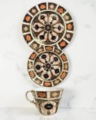 A Royal Crown Derby Imari porcelain teacup, saucer, and plate trio, unfilled gold band border,