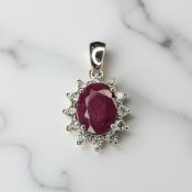 An 18ct gold ruby and diamond cluster pendant, the faceted oval ruby weighing an estimated 1.