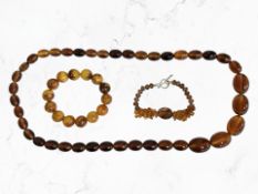 A group of simulated amber jewellery to include a graduated necklace and two bracelets.