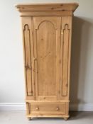 A 20th century pine single door wardrobe, with hanging rail within and fitted a drawer beneath,