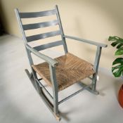 A painted wooden rocking chair with rattan seat
