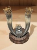An inkwell surmounted by two horns,