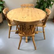 A contemporary pine circular dining table, diameter 110 cm, and four spindle back chairs.