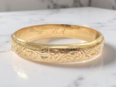 A 9ct yellow gold bangle with engraved decoration, 65 mm x 55 mm.