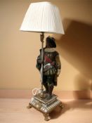 A figural painted silvered and gilt table lamp in the form of a Musketeer,