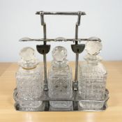 A chrome three bottle tantalus, width 33 cm.