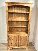 A modern pine open bookcase fitted cupboards beneath, 102 cm x 33 cm x 189 cm.