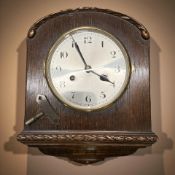 An early 20th century carved oak wall clock with silvered dial, with key, height 32 cm.