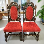 A pair of heavily carved oak barley twist hall chairs in brass studded red upholstery.