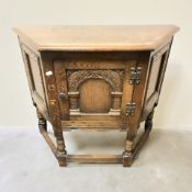 A reproduction carved oak single door cupboard,