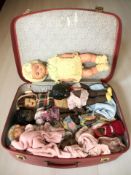 A vintage suitcase containing various dolls.