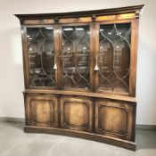 A Reprodux inverted bow front mahogany triple door bookcase, 175 cm x 45 cm x 183 cm.
