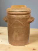 An earthenware twin handled crock pot with wooden lid, height 36 cm.