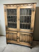 A reproduction oak linen fold bookcase, with leaded glass doors,