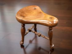 A reproduction mahogany saddle stool,