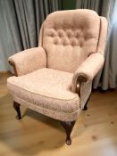 A reproduction lounge armchair in buttoned salmon floral fabric, width 85 cm.