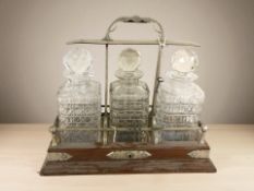 An oak and EPNS three bottle tantalus, height 36 cm, with key.