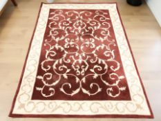 A machine-made rug on red and cream ground, 230 cm x 160 cm.