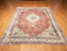 An Indian carpet, decorated with a cream pole medallion upon a salmon field of scrolling vines,