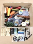 A collection of fishing equipment including various spools of line, thread, wooden gaff,