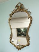 A good quality shield-shaped brass mirror with ribbon decoration, 93 cm x 51 cm.
