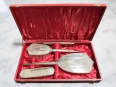 An Elizabeth II four-piece silver-backed dressing table set, comprising of a hand mirror,