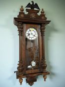 A late 19th century walnut Vienna wall clock with enameled dial and eagle pediment,