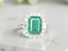 An 18ct white gold emerald and diamond cluster ring, size N.