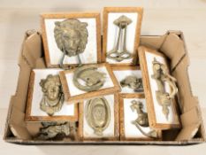 A group of cast brass door knockers mounted on boards.