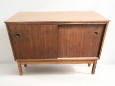 A 20th century teak sliding door side cabinet, 110 cm x 48 cm x 79 cm.