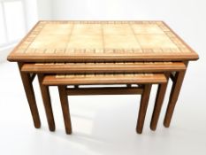 A teak tile inset nest of three tables, width 72 cm.