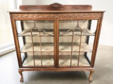 An Edwardian carved mahogany double door display cabinet on claw and ball feet,