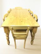 A stained pine 7 ft farmhouse-style dining table and a set of eight chairs.